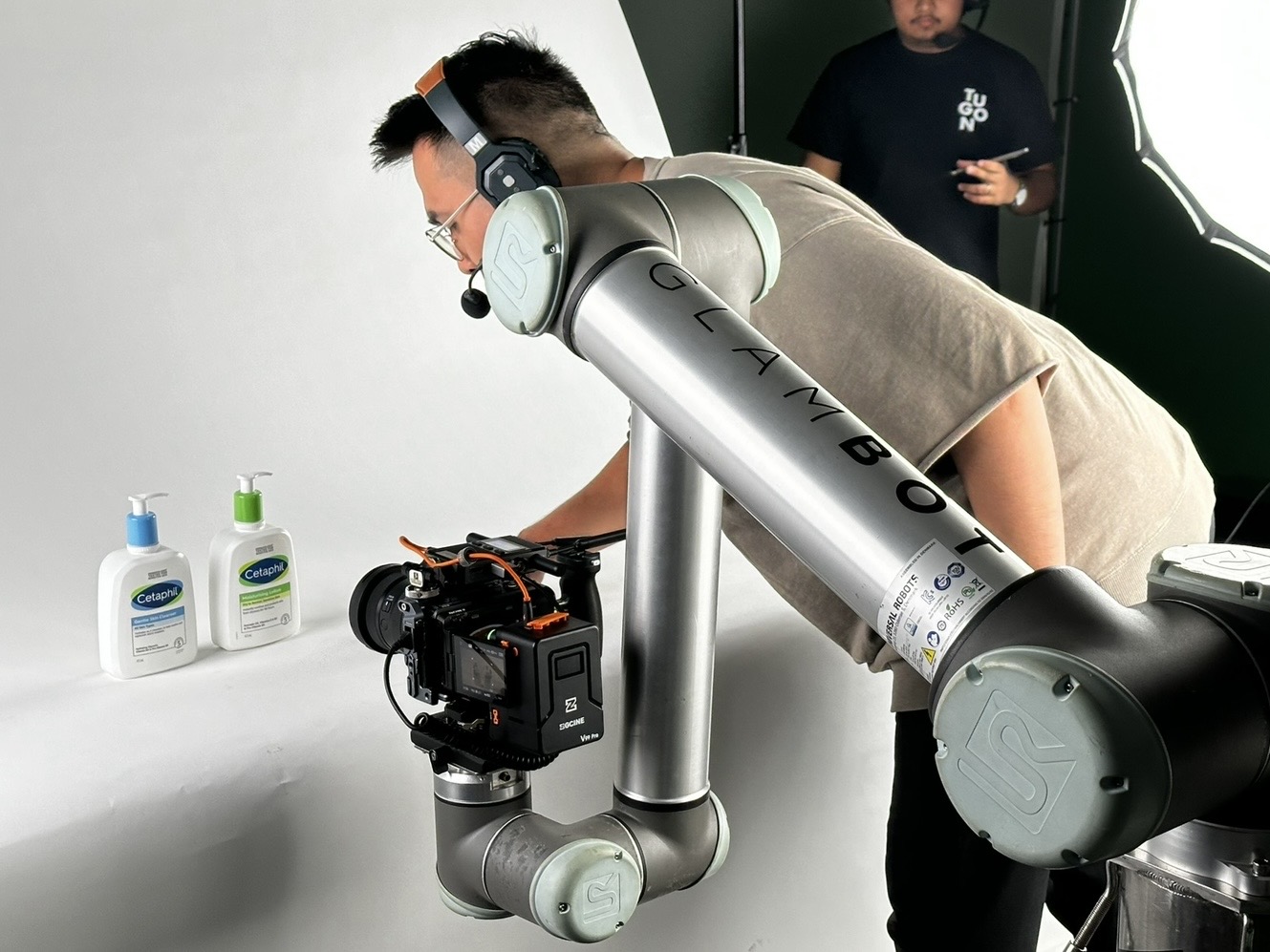 The GlamBot arm and camera rig lined up on Cetaphil bottles during a white-cyc product shoot